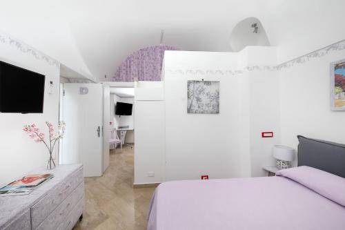 a white bedroom with a bed and a tv at Capri Dreaming in Anacapri