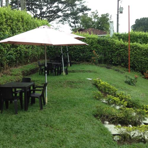 a table and chairs with an umbrella in the grass at Finca El Sueño De Mi Abuelo in Pereira