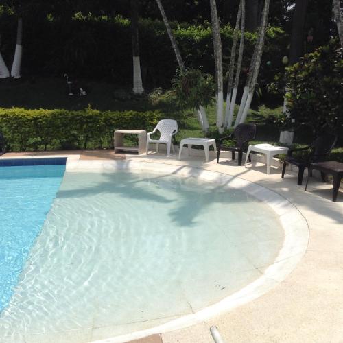 a large swimming pool with chairs and a table and sidx sidx at Finca El Sueño De Mi Abuelo in Pereira