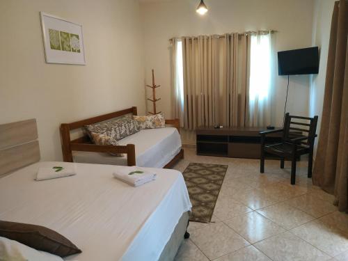 a hotel room with two beds and a desk at Mares de Camburizinho in Camburi