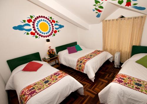 a room with three beds and a mural on the wall at Cusco Plaza Nazarenas in Cusco