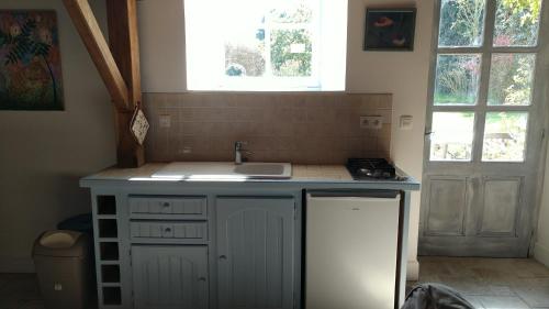 une petite cuisine avec un évier et une cuisinière dans l'établissement La Petite Maison, à Bricqueville