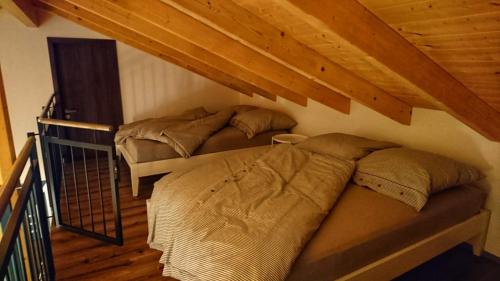 2 bedden in een zolderkamer met houten plafonds bij Ferienhaus sonnenWIND am Hainer See in Neukieritzsch