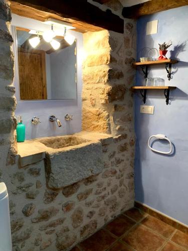 a stone bathroom with a sink and a mirror at Masia de la Serra de la Cogulla in Peñarroya de Tastavins