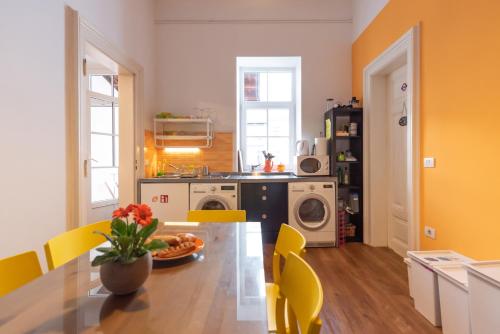 a kitchen with a dining table and yellow chairs at Fluxus Hostel in Ljubljana