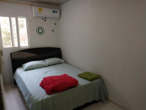 - une chambre avec un lit doté de draps rouges et une fenêtre dans l'établissement Apartamentos Maiver, à Ríohacha