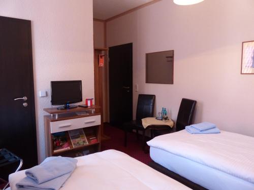 a hotel room with two beds and a television at Hotel Friedchen mit eigener Fleischerei in Artern