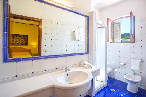 a bathroom with a sink and a toilet and a mirror at Hotel La Scogliera in Ischia