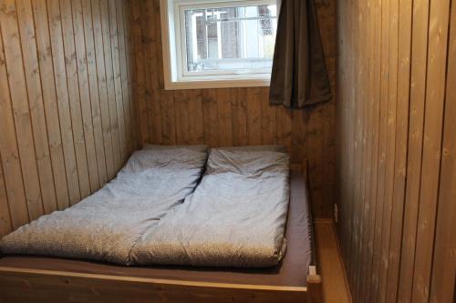 a small bed in a wooden room with a window at Geilotunet H224 - 6 person apartment in Geilo