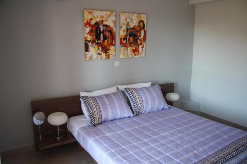 uma cama com lençóis e almofadas roxos num quarto em Thalatta Seaside Accommodation em Psilí Ámmos