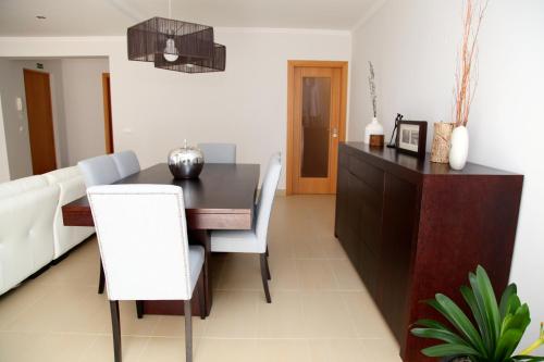 uma sala de jantar com uma mesa preta e cadeiras brancas em 20 da Vila - Apartment with Terrace em São Bartolomeu de Messines