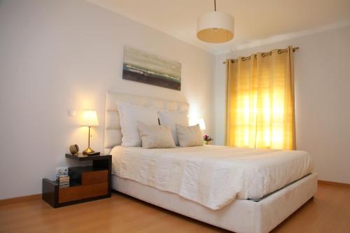 1 dormitorio con 1 cama blanca grande y ventana en 20 da Vila - Apartment with Terrace, en São Bartolomeu de Messines