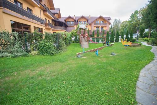 a yard with a playground in front of a house at Hotel Karino Spa in Polańczyk