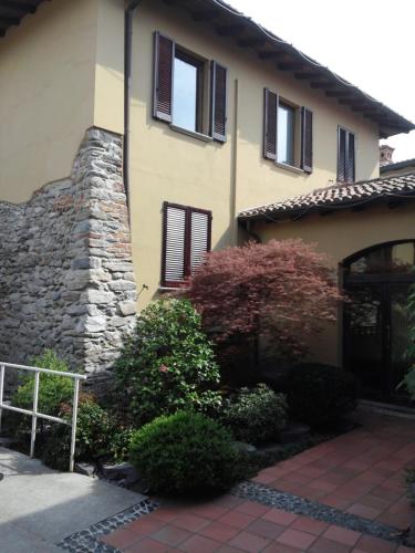 a house with a stone wall and windows and bushes at La Corte di Lurago in Lurago D'Erba 