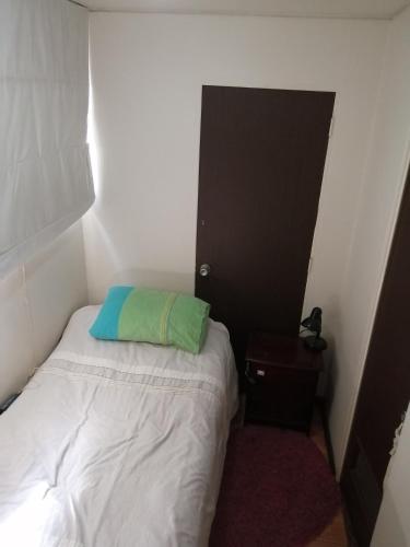 um pequeno quarto com uma cama com uma almofada verde em Katia em Santiago