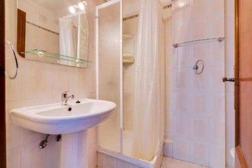 uma casa de banho branca com um lavatório e um chuveiro em Rei - Quarteira - 3 min to the beach em Vilamoura