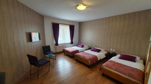 a hotel room with two beds and a chair at Hotel Zvonimir in Otočac