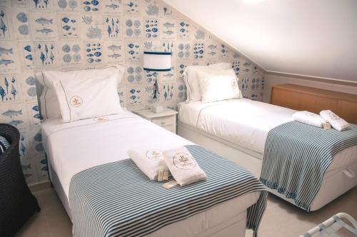 two beds in a room with blue and white wallpaper at Portuguese Wonders in Nazaré