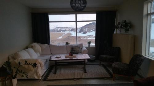 ein Wohnzimmer mit einem Sofa, einem Tisch und einem Fenster in der Unterkunft Hrafnabjörg 4 in Hrafnabjorg