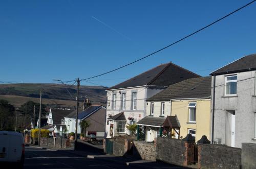a row of houses on a street with mountains in the background at The Cwtch, Log Fire, Sleeps 6, Nr Zip World, Brecon and Bike Park Wales in Aberdare