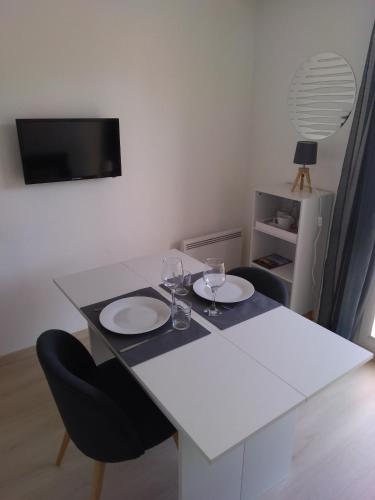 - une table blanche avec deux assiettes et des verres à vin dans l'établissement Résidence Le poisson d'or, à Perros-Guirec