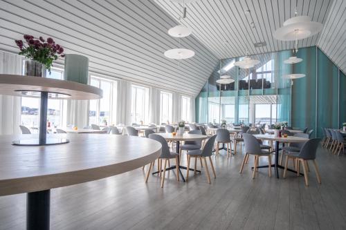 a dining room with tables and chairs and windows at Gullmarsstrand Hotell & Konferens in Fiskebäckskil