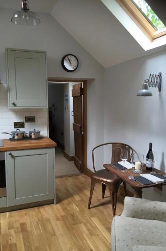 a kitchen and living room with a table and a clock at Providence Cottage a Sussex boutique retreat for two in Angmering