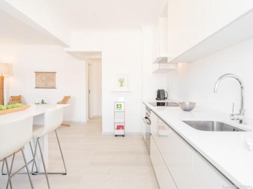 a white kitchen with white counters and a sink at Parede Ocean in Parede