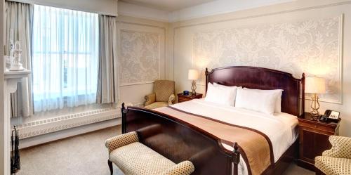 a bedroom with a large bed and two chairs at The Inn at the Union Club of British Columbia in Victoria