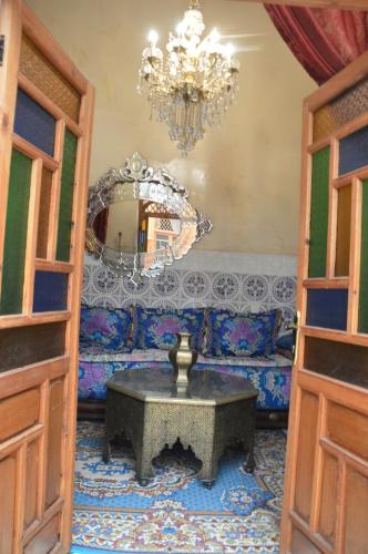 uma sala de estar com um sofá e um lustre em Riad Oumkaltoum Fès em Fez
