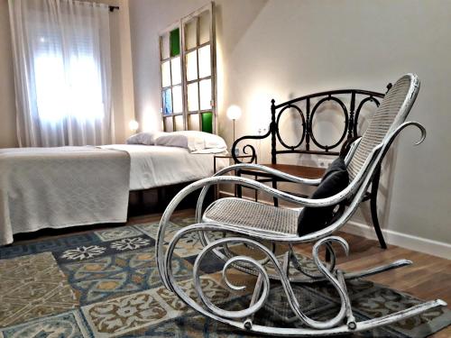 1 dormitorio con silla, cama y ventana en Urban Suites El Postigo, en Córdoba