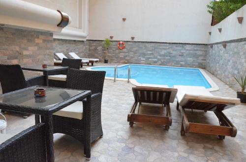 a patio with a swimming pool with chairs and a table at Elite Suites Hurghada in Hurghada