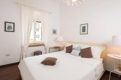 a white bedroom with a large white bed and a window at Novak Bonaparte - Hvar city center in Hvar