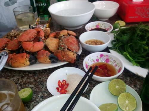 stół z talerzami żywności, pałeczkami i miskami żywności w obiekcie NHÀ NGHỈ PHƯƠNG THẢO w mieście Quan Lan