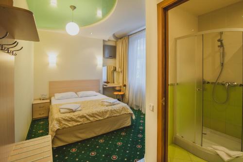 Habitación de hotel con cama y ducha en Hotel Coral Yalta, en Yalta