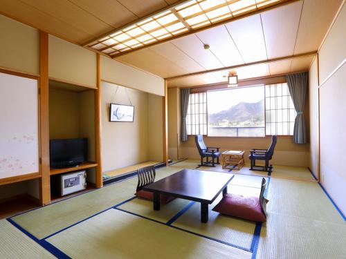 a living room with a table and chairs and a tv at Hotel Housei in Yamanouchi