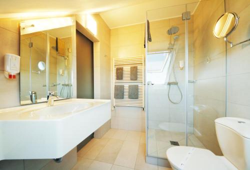 a bathroom with a tub and a shower and a sink at Hotel Saint Fiacre in Bourscheid