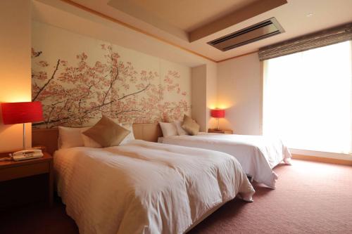 a bedroom with two beds and a painting on the wall at Hotel Futaba in Yuzawa