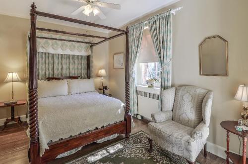 a bedroom with a canopy bed and a chair at Cedars of Williamsburg Bed & Breakfast in Williamsburg