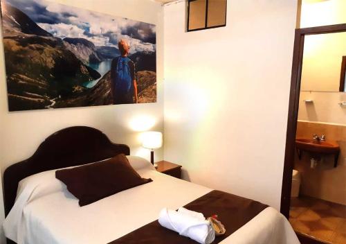 a bedroom with a bed with a painting on the wall at La Merced Plaza Hospedaje in Riobamba