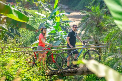 a man and a woman standing on a bridge with bikes at Katiliya Mountain Resort And Spa in Mae Salong Nai