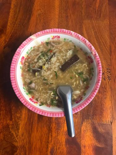a bowl of soup on a table with a spoon at Chansor Homestay 12 By Siem Reap Homesteading in Siem Reap