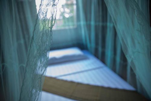 a bed in a room with a curtain at Chansor Homestay 12 By Siem Reap Homesteading in Siem Reap