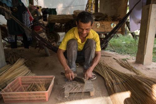 a man is cutting a piece of wood at Chansor Homestay 12 By Siem Reap Homesteading in Siem Reap