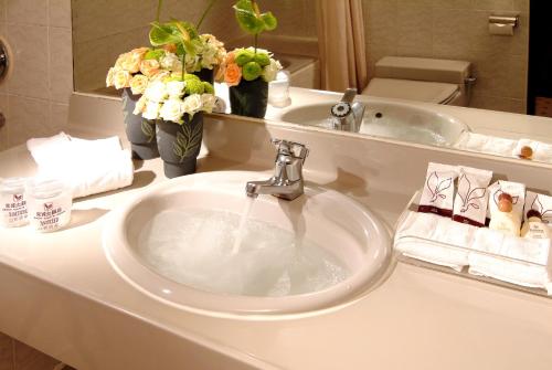 a sink in a bathroom with flowers and a mirror at King's Town Hotel in Kaohsiung