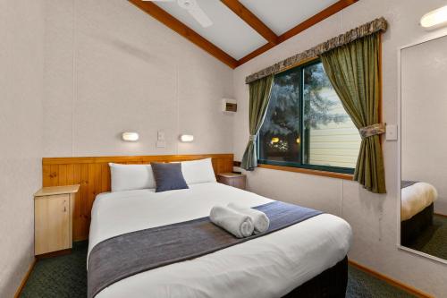 a bedroom with a large white bed with a window at Bright Riverside Holiday Park in Bright