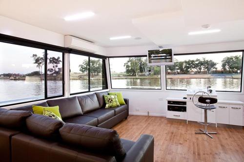 a living room with a couch and large windows at All Seasons Houseboats in Mildura