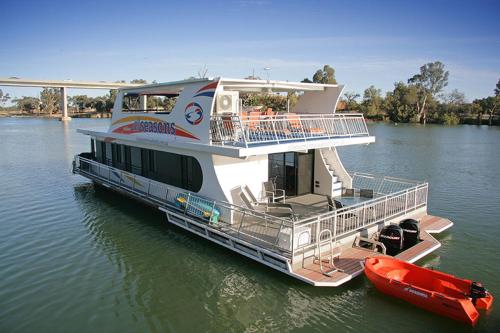 a boat parked on the water next to a red boat at All Seasons Houseboats in Mildura