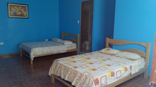 a bedroom with two beds and a blue wall at Hostal Virrey & Tours in Trujillo