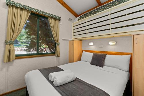 1 dormitorio con 2 camas y ventana en Bright Riverside Holiday Park, en Bright